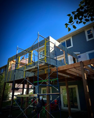 Construction of a house extension with scaffolding under a clear blue sky.