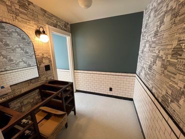A bathroom under renovation with patterned wallpaper and white subway tiles.