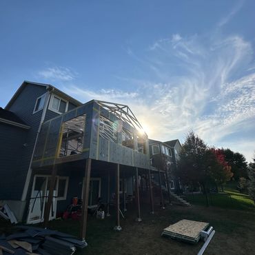 House extension under construction with wooden framework and clear blue sky.