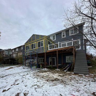 Snow-covered backyard with house undergoing construction extension.