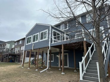 Blue house with elevated deck and staircase on a cloudy day.