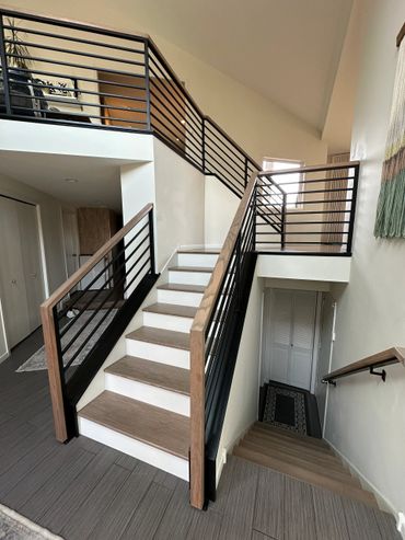 Modern indoor staircase with wood and black metal railings.