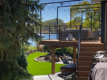 A cozy backyard deck overlooking a lake with string lights and outdoor seating.