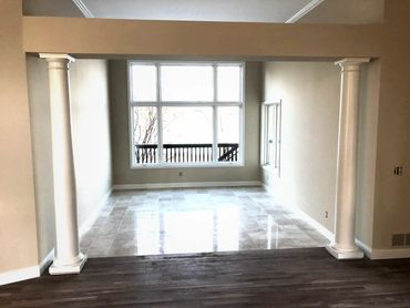 Empty room with two white columns and large window letting in natural light.