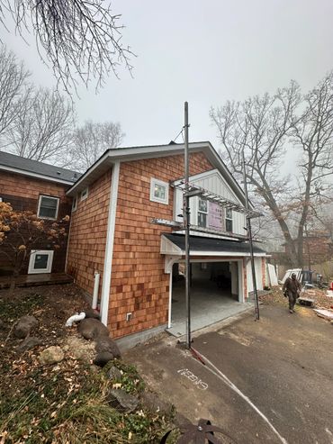 Newly constructed garage with fresh cedar siding and scaffolding in front.