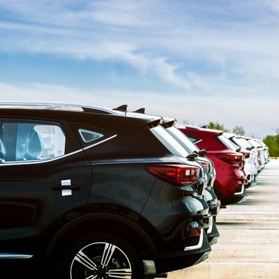 A row of parked modern SUVs in various colors under a partly cloudy sky.