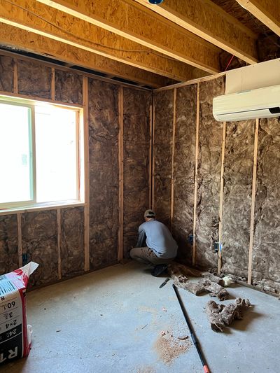 Worker installing insulation in a room under construction.