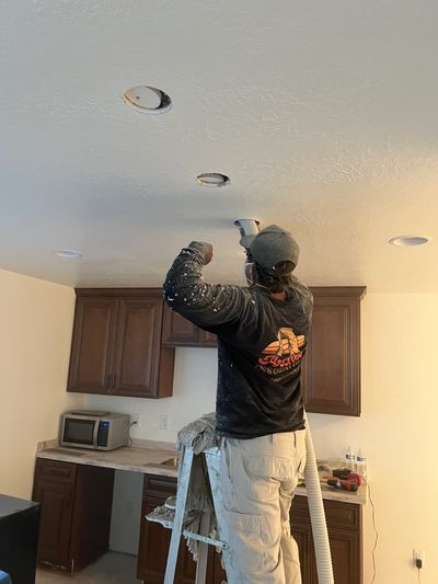 A man installing or repairing ceiling fixtures in a kitchen.