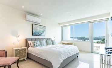Bright modern bedroom with large windows and ocean view.
