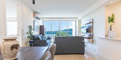 Bright living room with gray sofas and large windows showing a scenic view.