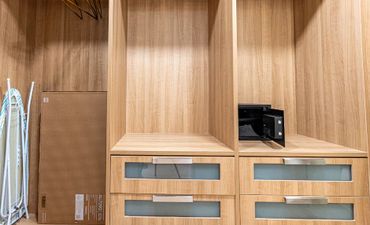 Empty wooden wardrobe with drawers and a small open safe inside.