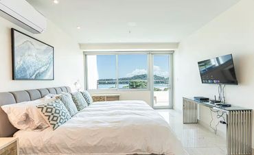 Bright bedroom with a large bed and a scenic ocean view through the window.