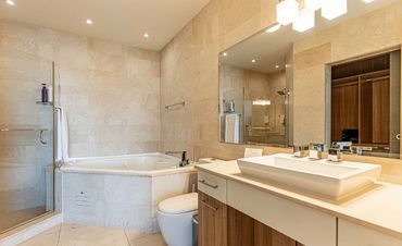 Modern bathroom with a bathtub, shower, and large mirror.