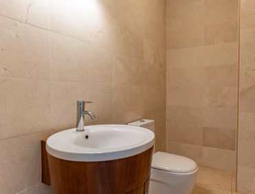Modern bathroom with wooden vanity and beige tiled walls.