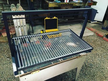 Metal grill frame with shiny rods on a workbench in a workshop.