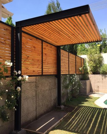 Modern wooden pergola with black metal frame casting striped shadows on the lawn.