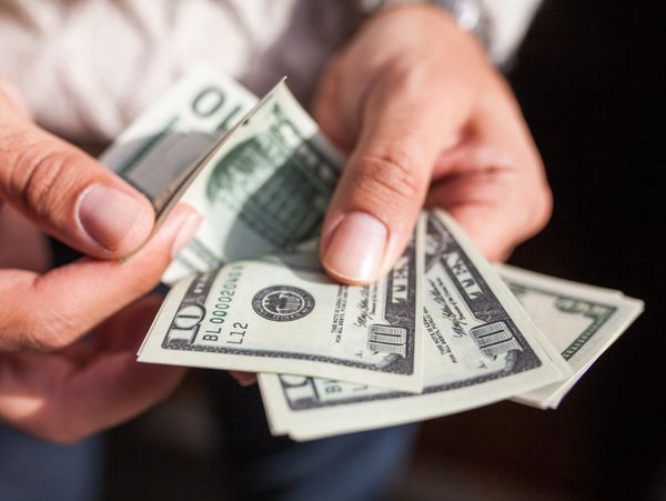 Two hands are counting and fanning out several ten-dollar bills.