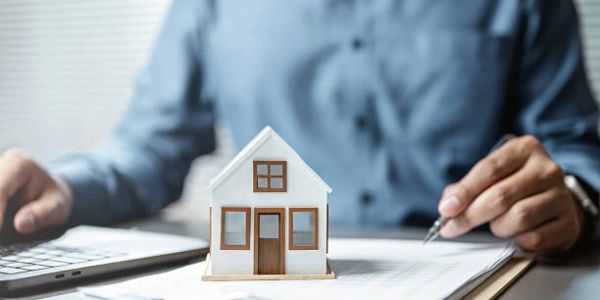 Person working with house model and documents.