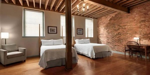 Modern bedroom with exposed brick wall and wooden beams.