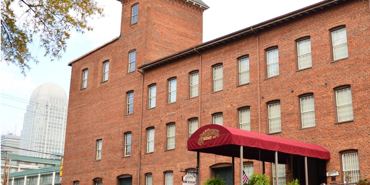 Old brick building with red canopy and city skyscraper in background.