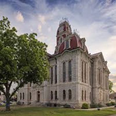 Historic courthouse building with a tall clock tower under a cloudy sky.