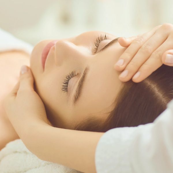 Woman receiving a relaxing facial massage with eyes closed.
