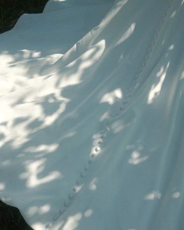 Close-up of a white fabric with buttons and dappled sunlight.