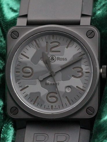 Close-up of a Bell & Ross BR 03-92 watch with a camouflage dial on green fabric.