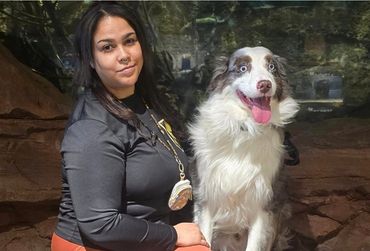 Woman posing with a happy, fluffy dog with bright blue eyes.