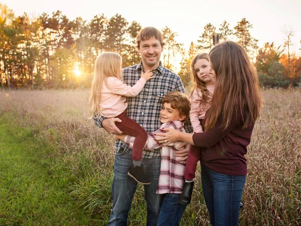 A family of five enjoying a sunny day outdoors in a field.