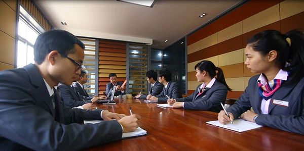 People seated around a conference table during a business meeting with notes and documents