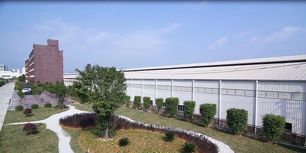 Exterior of an industrial production building with landscaped grounds and a brick-clad tower