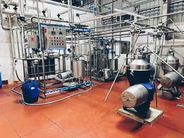 Industrial distillation equipment in a factory setting with metal pipes and tanks.
