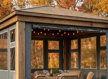 Outdoor patio structure with table and seating, structure is enclosed with Robie custom panels.