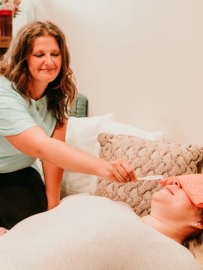 A woman checking another person's temperature with a thermometer.