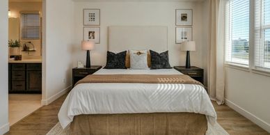 Modern bedroom with a large bed, bedside lamps, and natural light from windows.