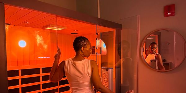 A woman stepping into a hot infrared sauna in the HaloHeat Sauna Studios private suite.