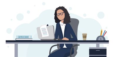 Businesswoman working on laptop at office desk with coffee and stationery.
