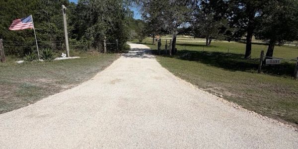 A gravel road leading through a rural area with American flags.