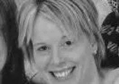 Black and white close-up portrait of a smiling woman with short hair.
