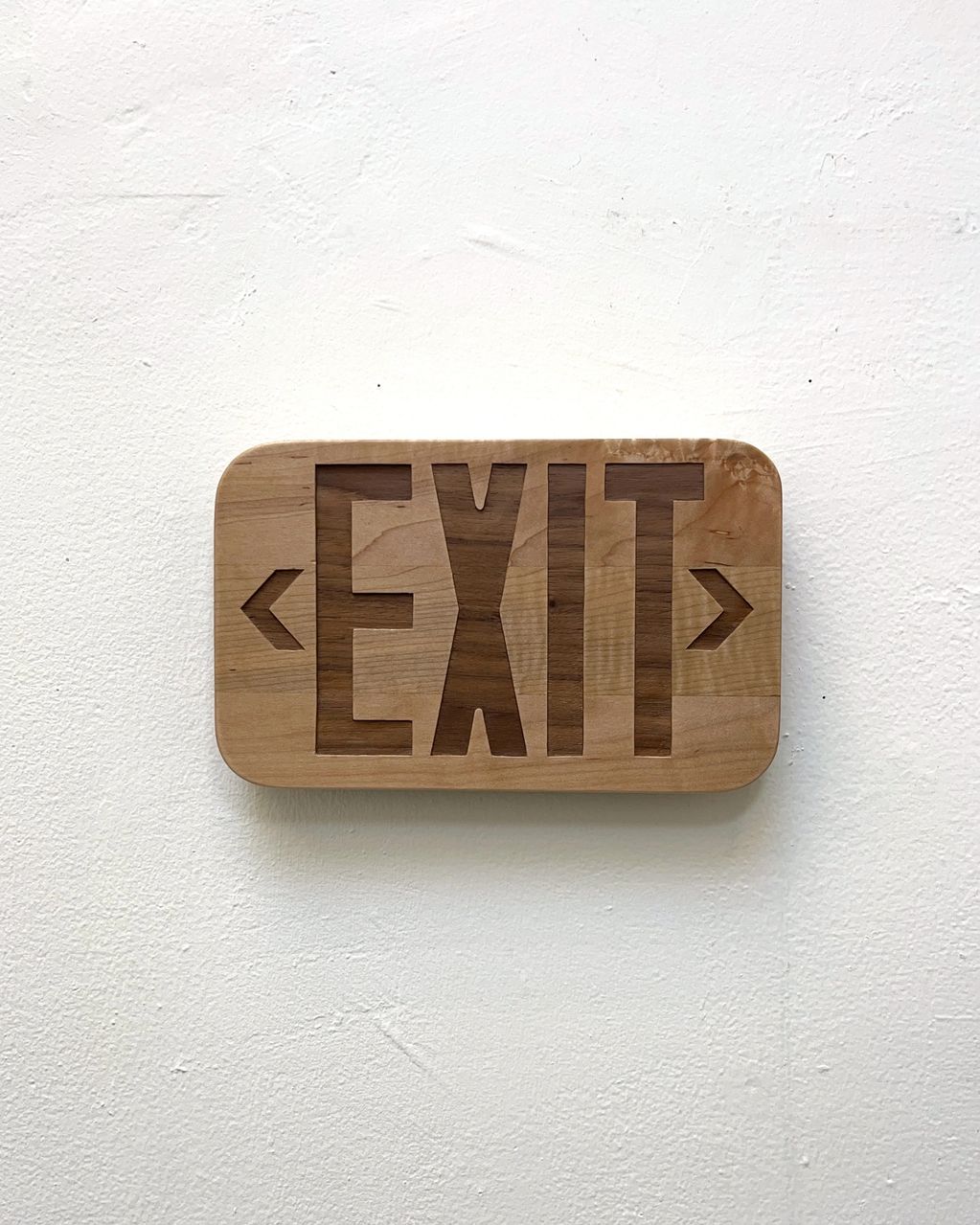 Wooden exit sign carved into a block mounted on a wall.