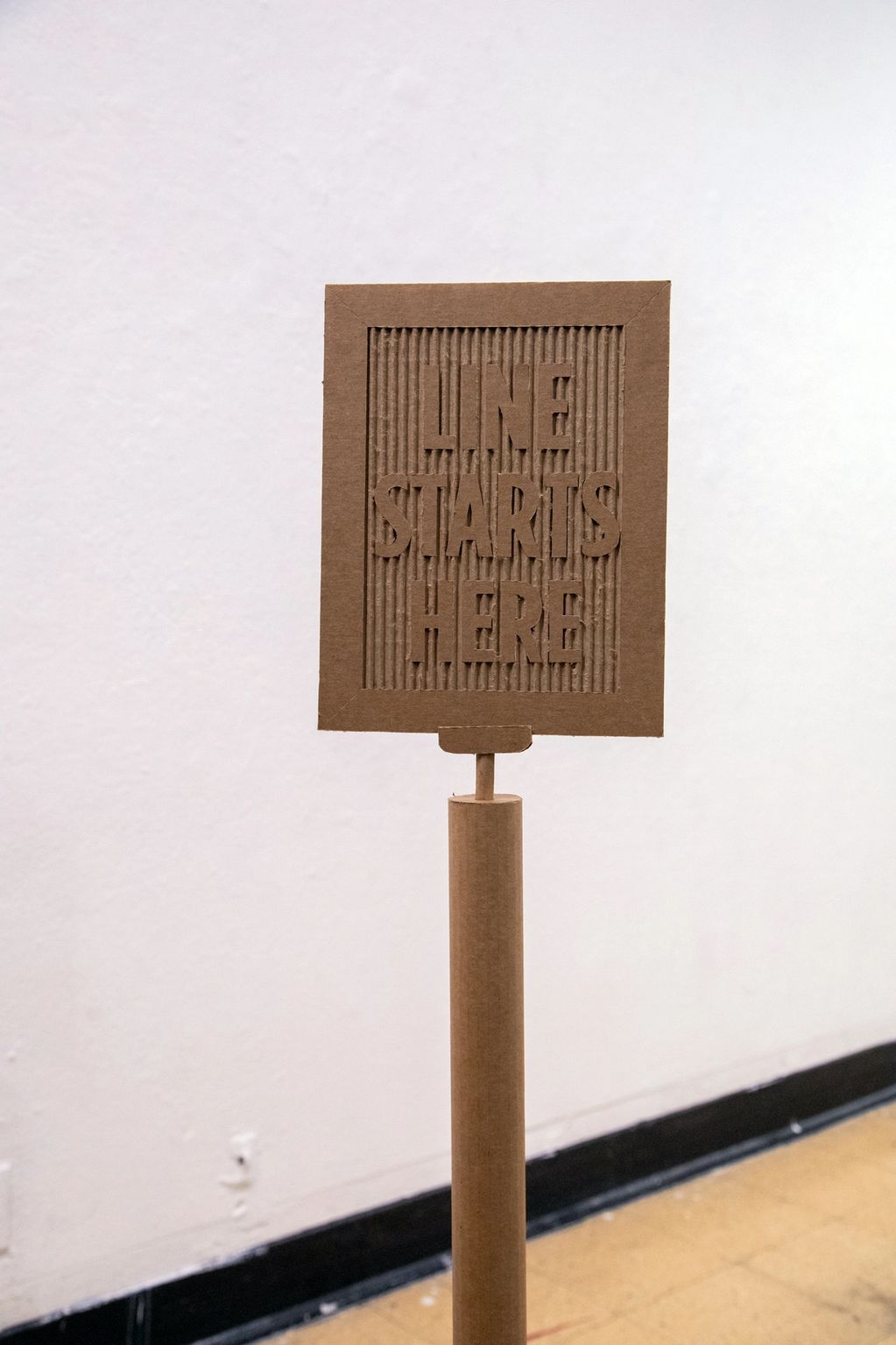 Cardboard sign with 'LINE STARTS HERE' message.