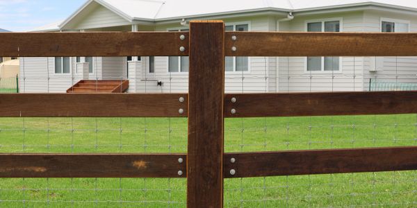 Wooden fence with wire mesh in front of a modern house.