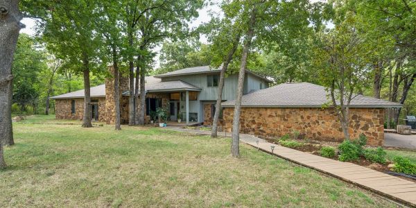 Large house with stone exterior surrounded by trees.