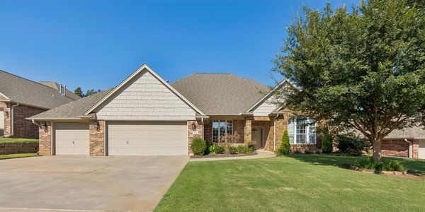 Large suburban house with a three-car garage and green lawn.