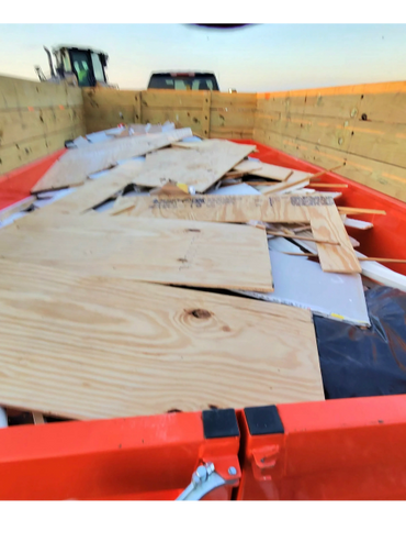 Wood scraps and debris loaded in an orange trailer with wooden sides.