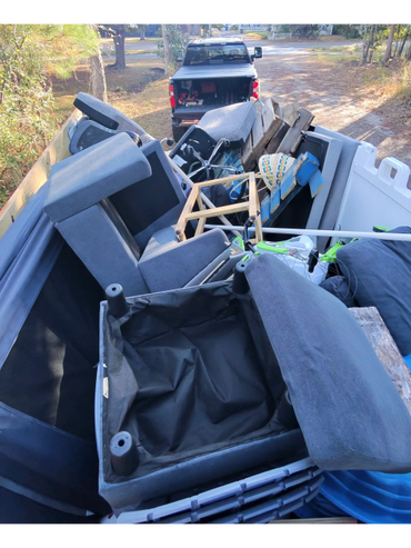 Truck loaded with old furniture and wooden pallets on a rural road.