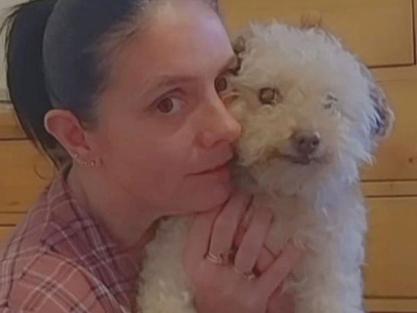 Woman hugging a small white dog.
