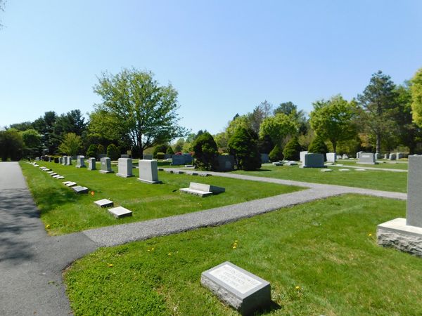 A peaceful cemetery with green grass and clear blue sky.