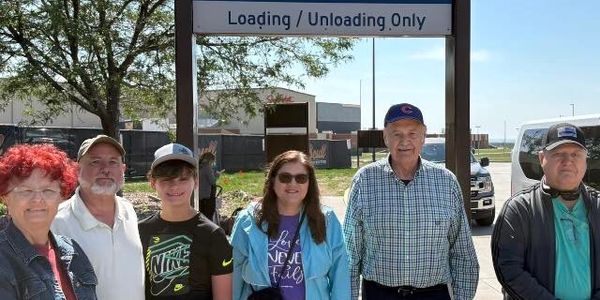 Group of six people standing under a Departing Flights sign at an airport.